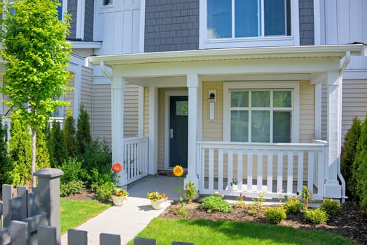 Residential townhouse with open patio under the porch. Attached residential house on bright sunny spring day