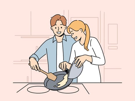Married couple prepares breakfast enjoying sunday morning and experiencing happiness from communicating with loved one. Happy couple of man and woman cooking pancakes or omelet together