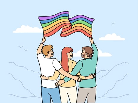 Group of people with LGBT flag travel with pride community and admire beautiful nature. Two man and woman hugging holding lgbt banner calling to be more tolerant towards lesbians or transgenders