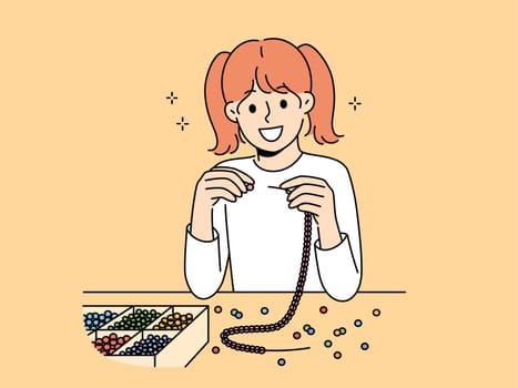 Little girl weaves beaded jewelry sitting at table and creating handmade necklace or bracelet. Elementary school girl with creative hobby creates jewelry and wants to be designer when grows up.