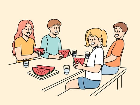 Children eat watermelon sitting at table and enjoying sweet refreshing dessert on hot summer day. Childrens picnic for boys and girls with delicious watermelon containing healthy vitamins