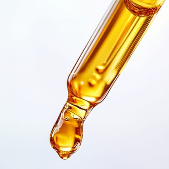 Golden liquid drop from glass dropper on clean background for beauty and skincare concepts