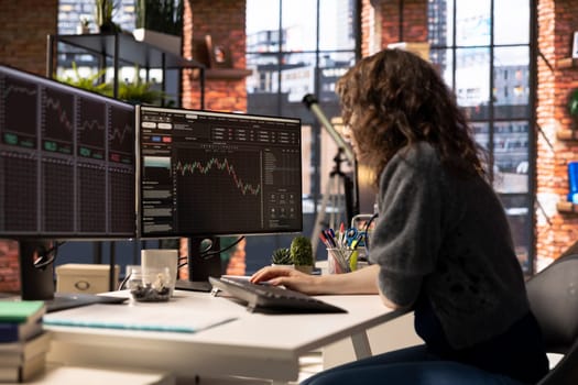 Young woman studies stock trading charts on her computer, browsing through financial analysis tools. The trading platform provides statistics, forex trends and index for profitable investments.