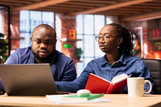 African American man and woman sits at a stylish home office, brainstorming ideas for their digital business, using modern technology to improve communication and project efficiency.