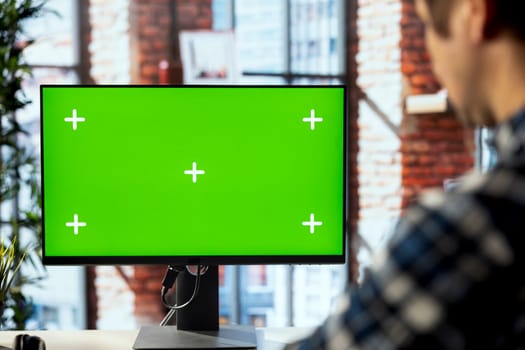 Man in workspace engaging in online training session on isolated screen PC, navigating course modules. Employee in home office watching instructional company videos on mockup computer monitor, closeup