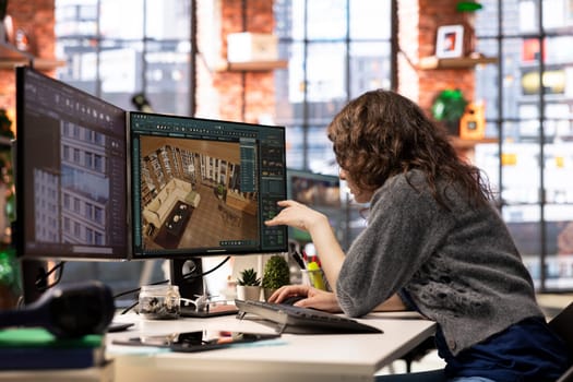 Designer interacts with digital technology to produce a virtual home set. The architectural software enables 3D modeling and rendering, allowing placement of furniture and layout adjustments.