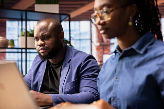 African American couple in their home office collaborate on a business project, using teamwork and digital online tools to enhance efficiency and career growth. Solving freelancing tasks.