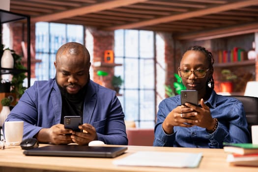 African american freelancers couple check email correspondence on smartphones, sending mails before starting daily work tasks. Young man and woman working remotely at their home.