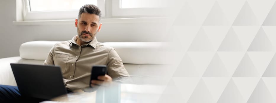 A middle aged businessman works diligently at a contemporary office space. He uses a laptop and mobile phone, reflecting a corporate lifestyle focused on success and productivity, copy space