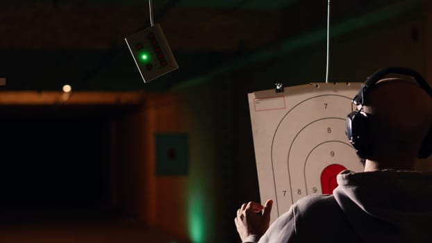 Group of friends in firing range doing recreational shooting activity with firearm, hitting bullseyes. People in shooting gallery training with handguns, sharpening skills, camera B