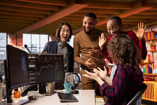 Startup team celebrating in office after successful IPO, watching live market updates showing stock surging. Venture employees excited after securing funding to become publicly traded company