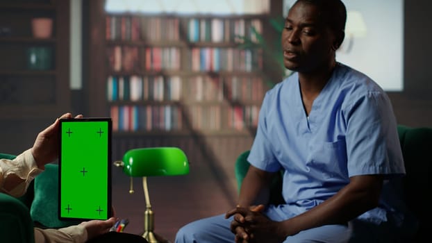 Nurse in counseling session coping with patients loss next to green screen, deals with mental health challenges. African american assistant working in a hospital with PTSD and trauma. Camera B.