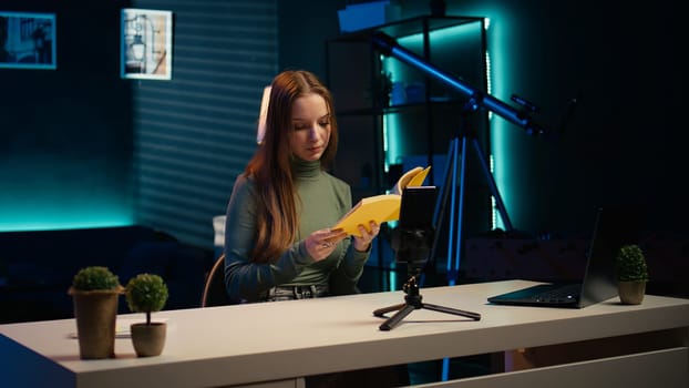 Young influencer filming review of light bulb able to change into different colors. Content creator showcasing smart home automation technology in apartment studio, camera B