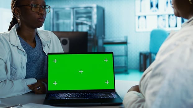 General practitioner meeting with young girl next to chroma key screen, health care practice for disease prevention. Expert offers advice for wellness, routine consultation in the office. Camera B.