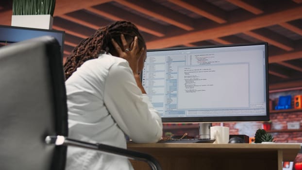 Irked software developer frustrated while coding, struggling to implement algorithms. Unhappy IT expert annoyed while working with code editor, unable to optimize performance, camera B