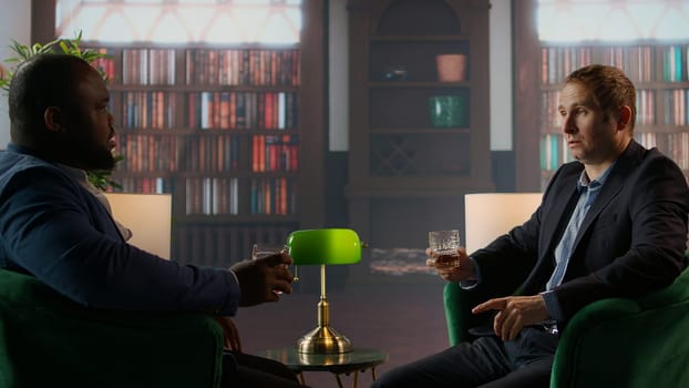 Gallant investor consultant engage in a meaningful conversation with a friend, enjoying a fine scotch and making propositions for a new business opportunity at the elite social club. Camera A.