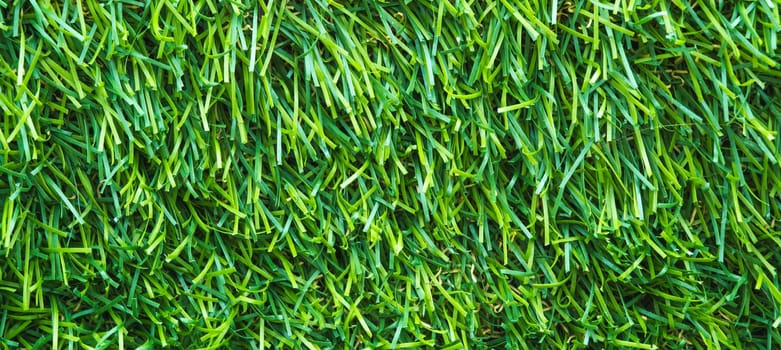 artificial lawn background with green grass texture close-up with a copy space