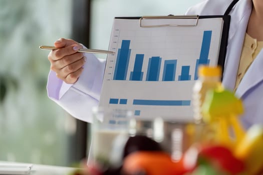A well-dressed doctor showcases bar graphs on a clipboard, emphasizing the importance of nutritional monitoring for patients in a professional setting.