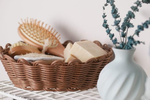 Stylish basket holds grooming tools and soap beside a vase with flowers.
