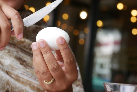 A woman carefully cuts a boiled egg in a warm, inviting atmosphere.