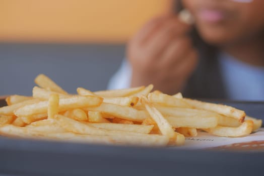 Delicious fries are placed prominently on a table while someone enjoys them.