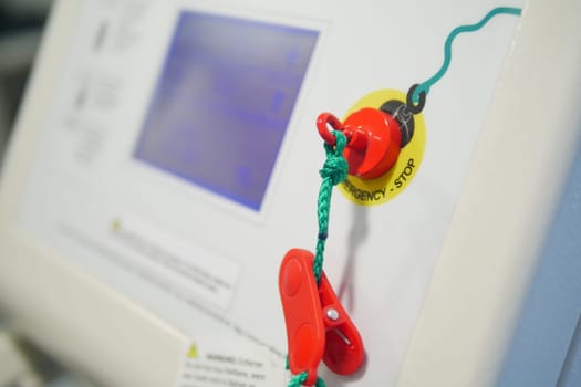 Bright red emergency stop button is prominently visible on equipment.