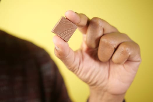 Person presents a small chocolate piece with a vibrant backdrop.