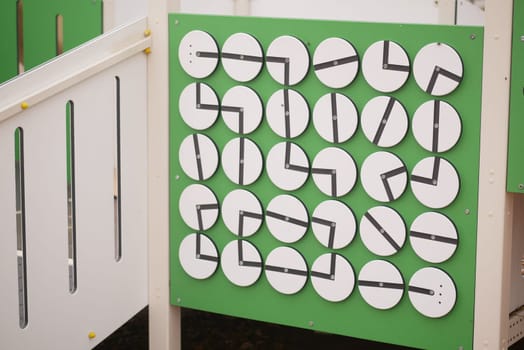 Children eagerly explore a clock face activity at a playground.