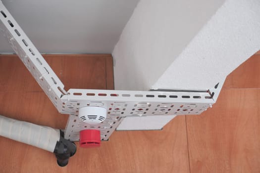 Metal brackets and a fire alarm are securely mounted in a building.