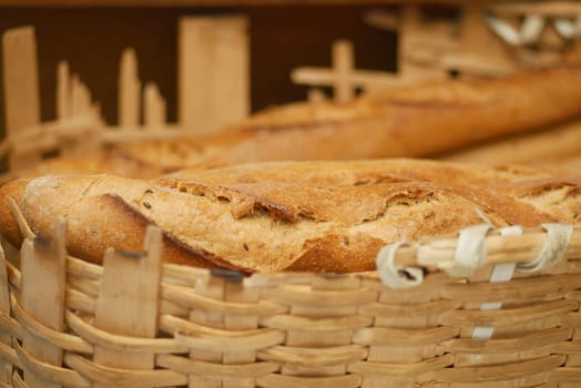 A warm loaf of bread rests in a woven basket, showcasing its crusty texture.