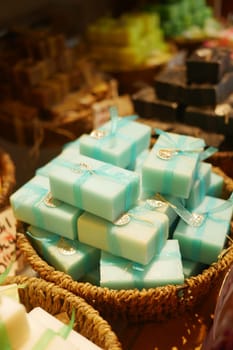 Multiple bars of handmade soap are arranged in a woven basket.