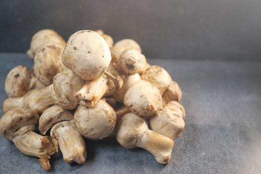 A collection of fresh white mushrooms piled on a gray surface.