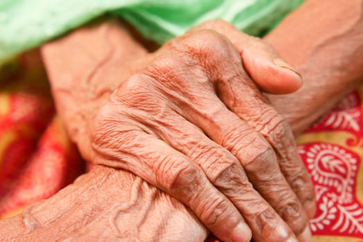 An elderly person's hands are clasped together, showing age and wisdom.