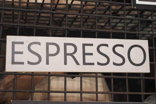 A prominent sign for espresso is showcased in an energetic cafe environment.