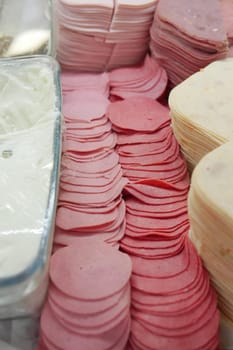 Sliced deli meats and spreads neatly arranged on display in a market.