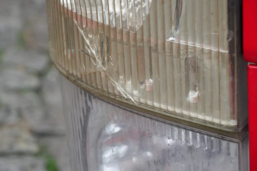 Close view of a cracked tail light reflecting light on cobblestones