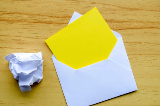 Top view of empty yellow notepad inside an envelope with crumpled paper with customizable space for text.