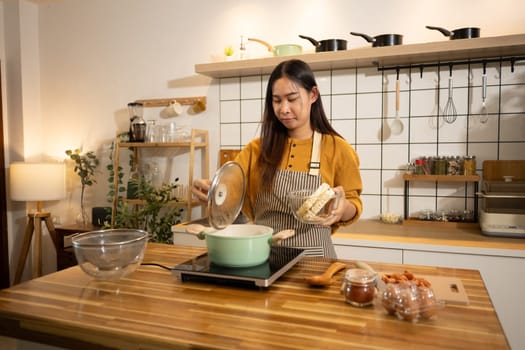 Happy young woman preparing instant noodles in a stylish modern kitchen.