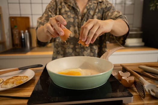 Close up shot of young man cracking an egg into a frying pan.