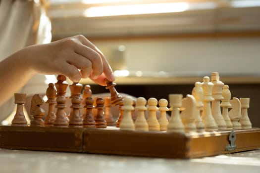 Hand moving a chess piece on wooden board. Strategy, decision making and board games concept.