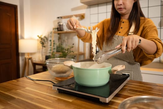 Happy young woman preparing instant noodles in a stylish modern kitchen.