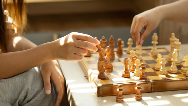 Close up shot of two players playing chess in a sunlit room.
