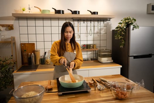 Young woman in an apron cooking a simple meal in her home kitchen.