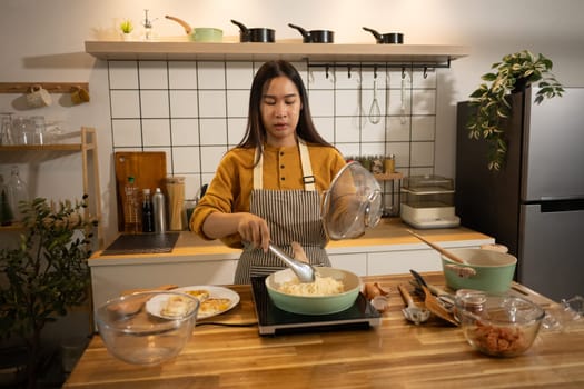 Happy young woman preparing instant noodles in a stylish modern kitchen.