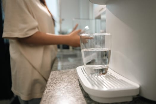 A glass of clean drinking water on water purifier in a modern kitchen.