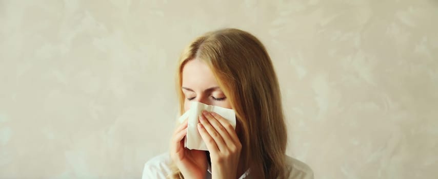 Sick exhausted young woman sneezing blow nose using tissue, unhealthy suffering girl feels unwell at home