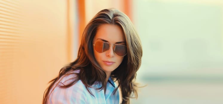 Portrait of beautiful brunette young woman in sunglasses posing in the city