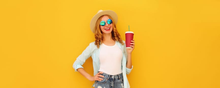 Summer vacation, joyful young woman with cup of coffee, stylish modern girl drinking fresh juice in tourist straw hat posing on yellow background