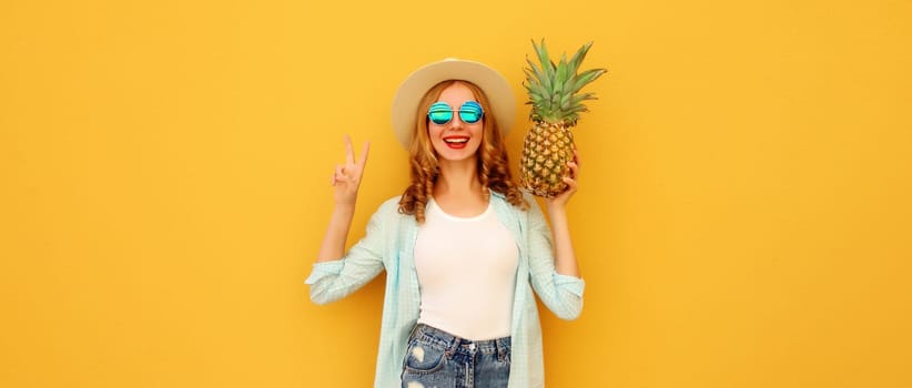 Summer vacation, happy joyful young woman with pineapple fruit in tourist hat, cheerful girl posing on yellow studio background