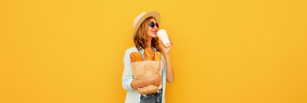 Happy modern bakery customer young woman holding grocery shopping paper bag with long white bread baguette drinking coffee on bright yellow background